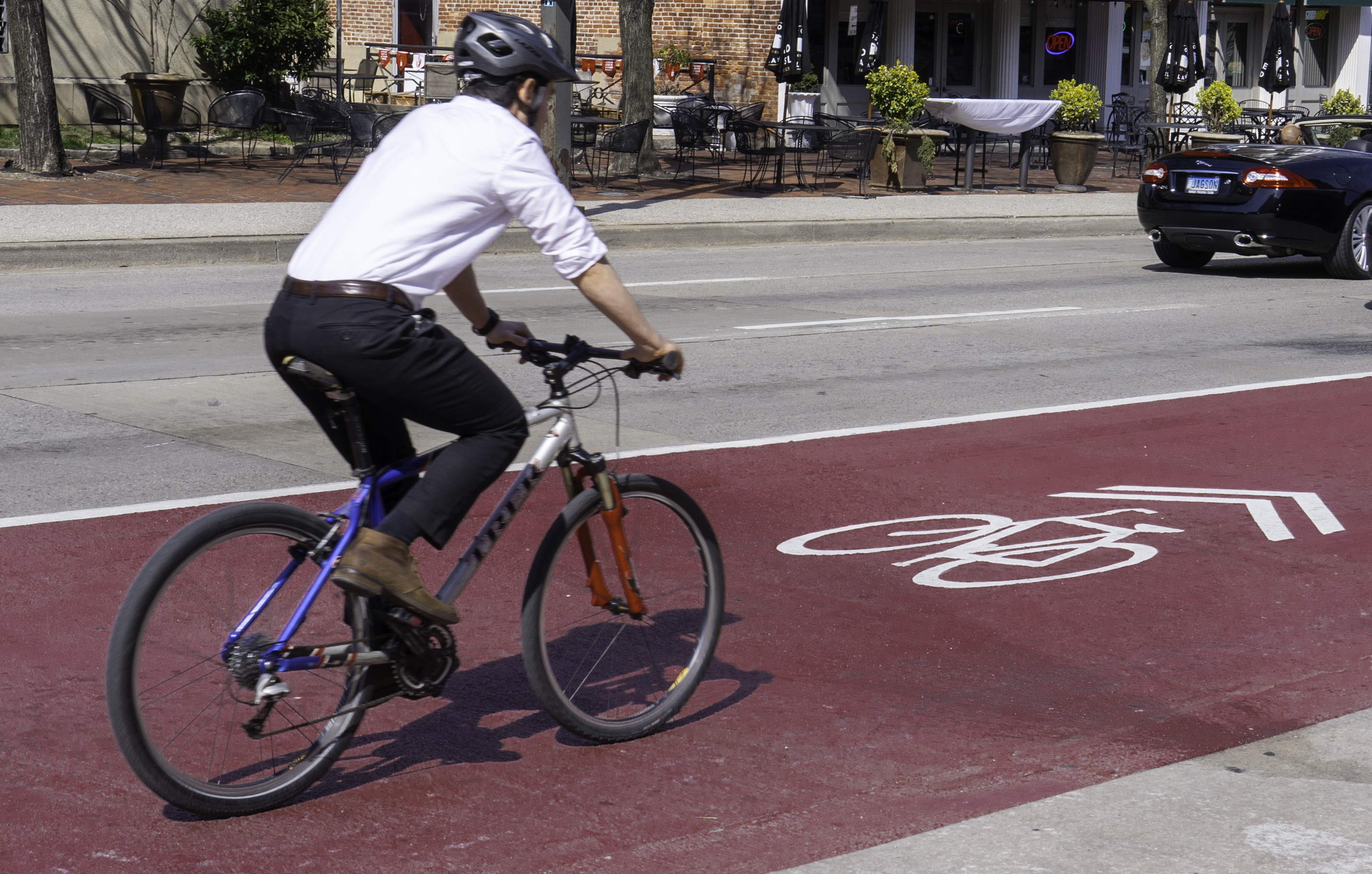 Photo of professionally dressed man riding bike in a marked bike lane